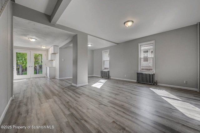 unfurnished living room with radiator, baseboards, and wood finished floors