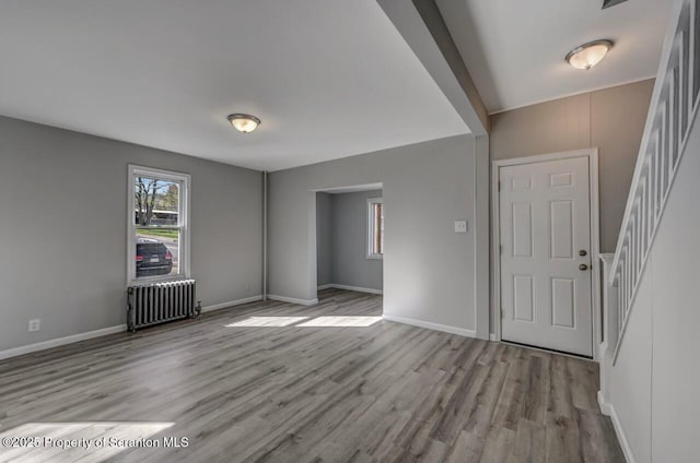 entryway with radiator heating unit, baseboards, stairs, and wood finished floors