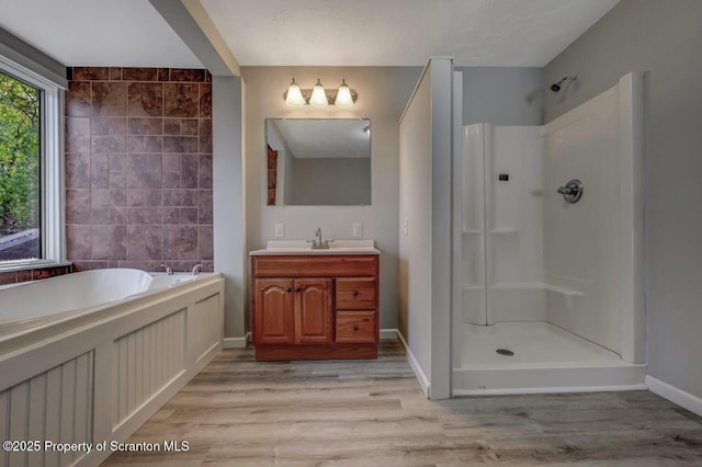 bathroom with a garden tub, walk in shower, wood finished floors, and vanity