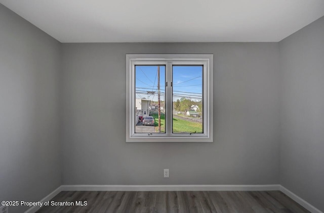 unfurnished room with baseboards and wood finished floors