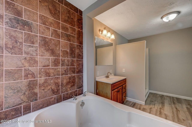 full bath with vanity, baseboards, a tub to relax in, and wood finished floors