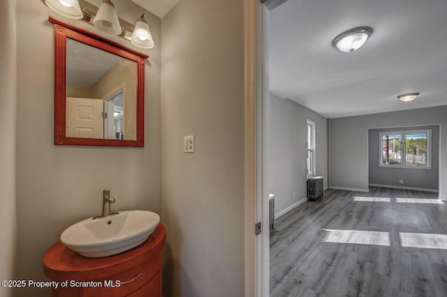 bathroom with baseboards, radiator, wood finished floors, and vanity