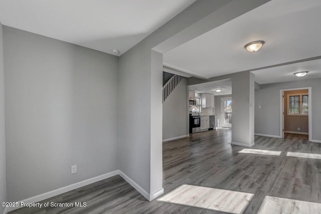 unfurnished living room featuring baseboards and dark wood finished floors