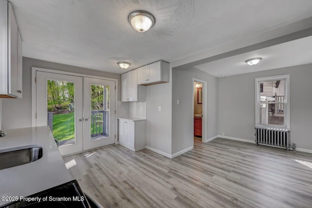 kitchen featuring light countertops, radiator, white cabinets, and french doors