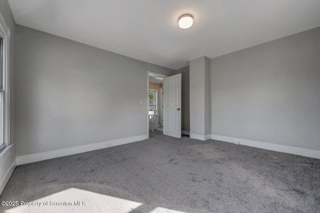 carpeted empty room featuring baseboards