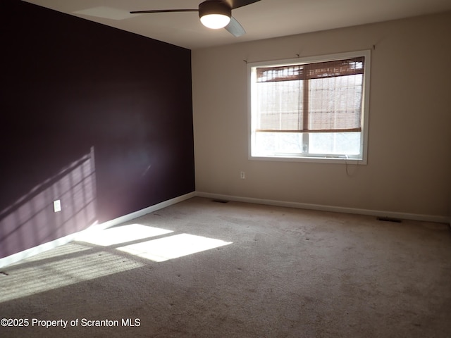 carpeted spare room featuring ceiling fan