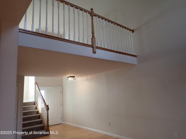 staircase with wood-type flooring and a high ceiling