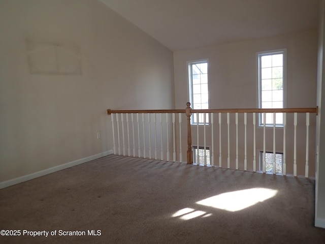 carpeted empty room with lofted ceiling