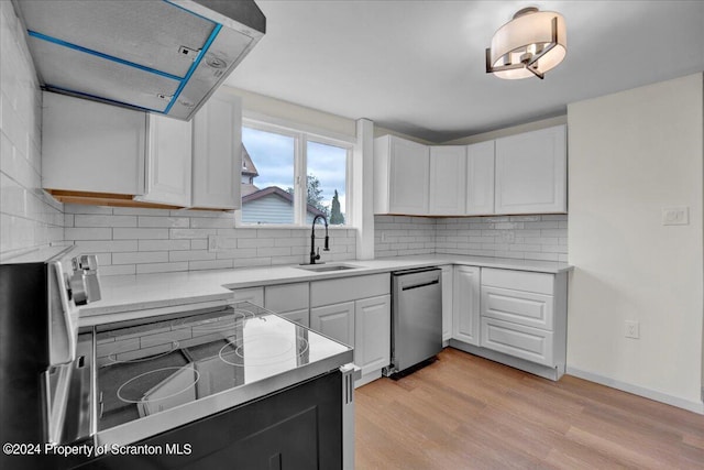 kitchen with backsplash, stainless steel appliances, sink, white cabinets, and light hardwood / wood-style floors