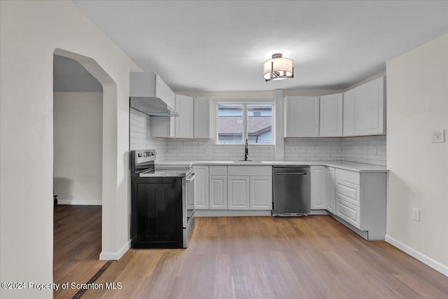 kitchen featuring backsplash, stainless steel appliances, white cabinetry, and wall chimney exhaust hood