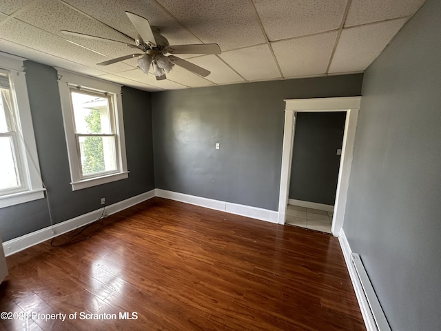 1518 Vine St, Scranton, PA 18510 - empty room with a baseboard heating unit, wood finished floors, a ceiling fan, baseboards, and a paneled ceiling