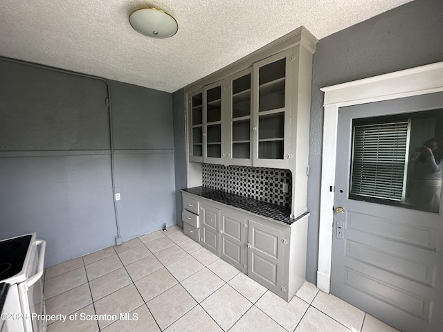 1518 Vine St, Scranton, PA 18510 - kitchen with a textured ceiling, light tile patterned floors, white electric range, glass insert cabinets, and dark countertops