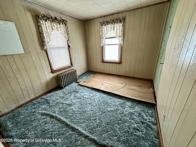 spare room featuring wood walls and radiator heating unit