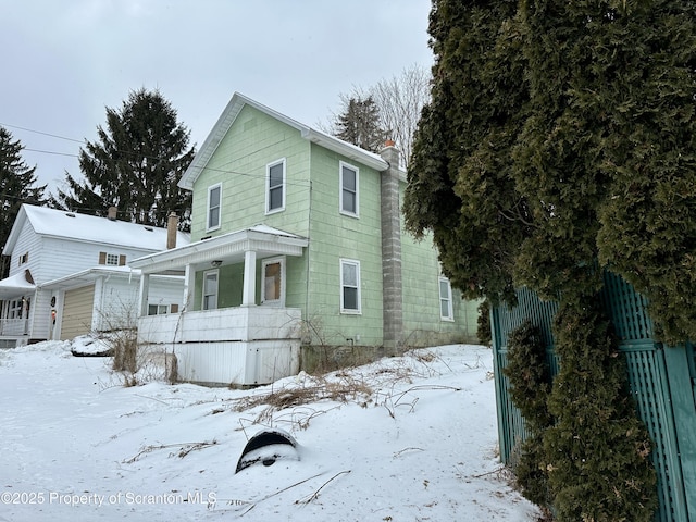 view of front of home featuring a chimney and a porch