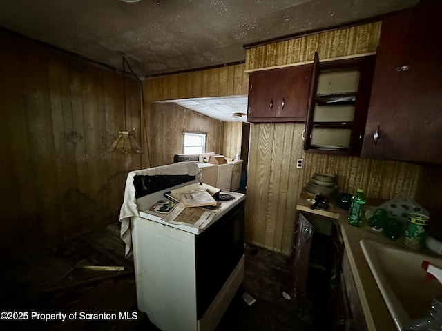 kitchen with washer / dryer, brown cabinets, light countertops, wood walls, and a sink