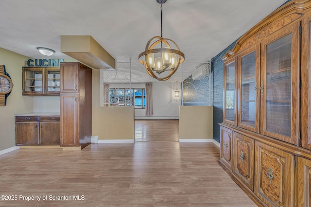 unfurnished dining area with an inviting chandelier, light hardwood / wood-style floors, and a baseboard heating unit