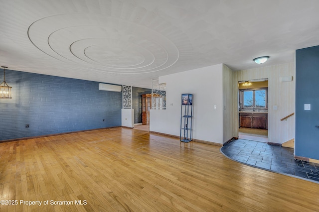 unfurnished living room featuring a wall mounted air conditioner, a notable chandelier, and light wood-type flooring