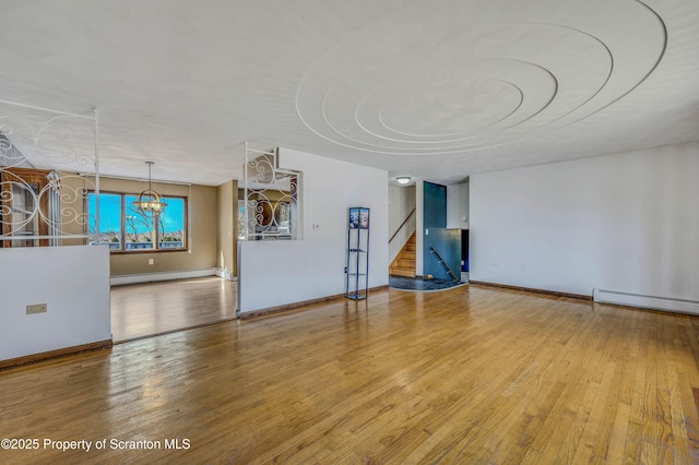 unfurnished living room with wood-type flooring, a chandelier, and baseboard heating