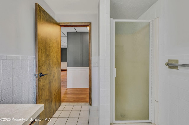 bathroom with walk in shower, tile patterned floors, tile walls, and vanity