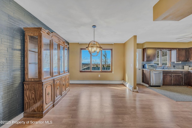 unfurnished dining area with light wood-type flooring, ceiling fan with notable chandelier, and baseboard heating