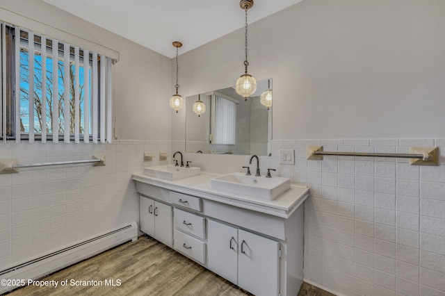 bathroom with a baseboard radiator, hardwood / wood-style floors, vanity, and tile walls