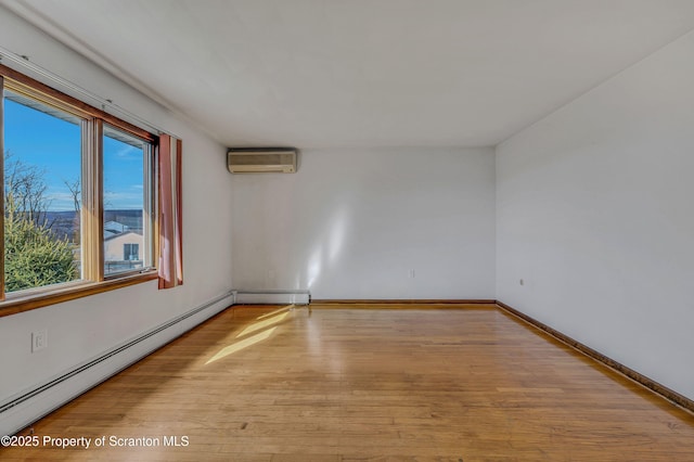 empty room featuring a baseboard radiator, a wall mounted AC, and light hardwood / wood-style floors