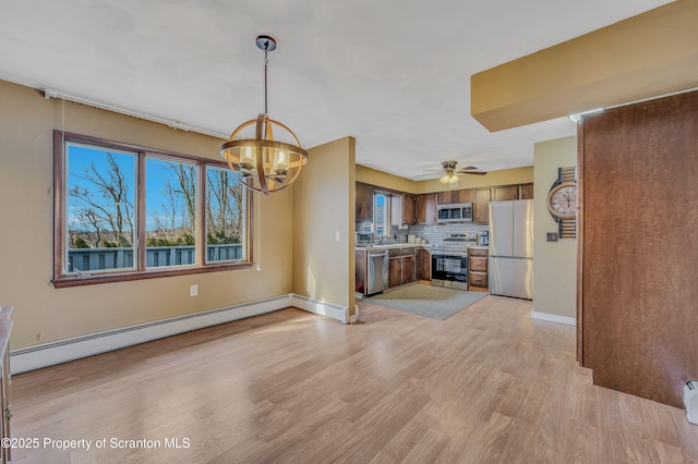 kitchen with pendant lighting, light hardwood / wood-style flooring, appliances with stainless steel finishes, backsplash, and a baseboard radiator