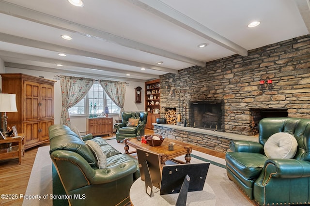 living room featuring beam ceiling, light hardwood / wood-style flooring, and a stone fireplace