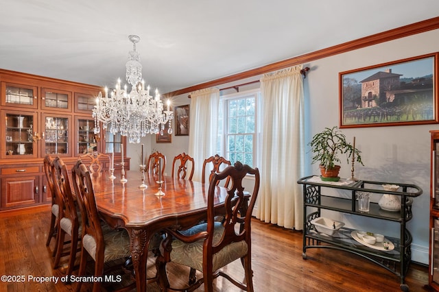 dining area with crown molding, dark hardwood / wood-style floors, and an inviting chandelier