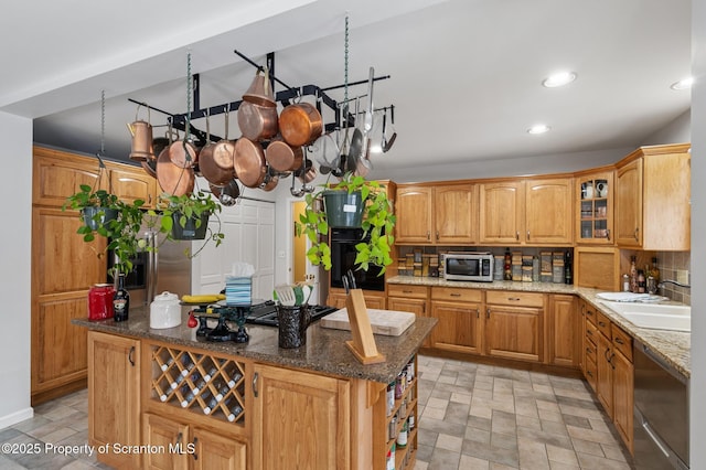 kitchen with dark stone countertops, sink, stainless steel appliances, and a kitchen island