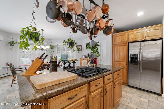 kitchen with hanging light fixtures, black gas cooktop, a center island, stainless steel fridge with ice dispenser, and dark stone counters