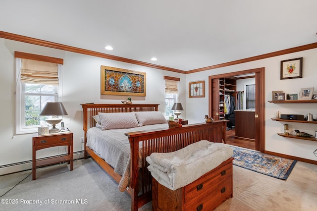 carpeted bedroom with a baseboard heating unit, a walk in closet, ornamental molding, and a closet