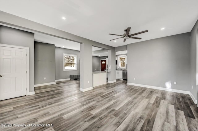 unfurnished living room with recessed lighting, radiator heating unit, a ceiling fan, wood finished floors, and baseboards