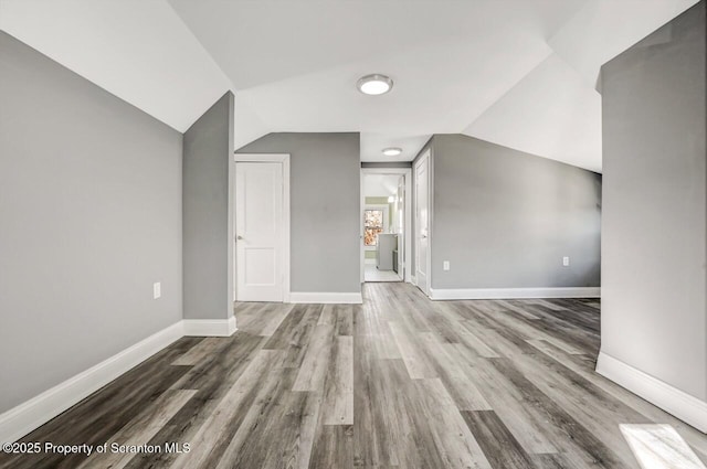 bonus room featuring lofted ceiling, baseboards, and wood finished floors