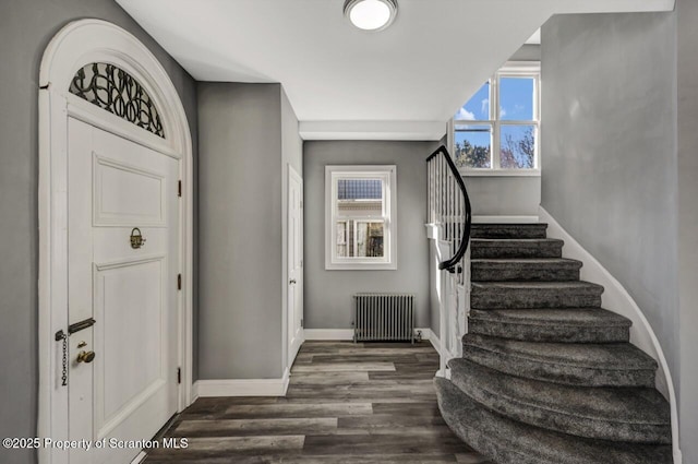 foyer entrance featuring dark wood-type flooring, radiator, stairway, and baseboards