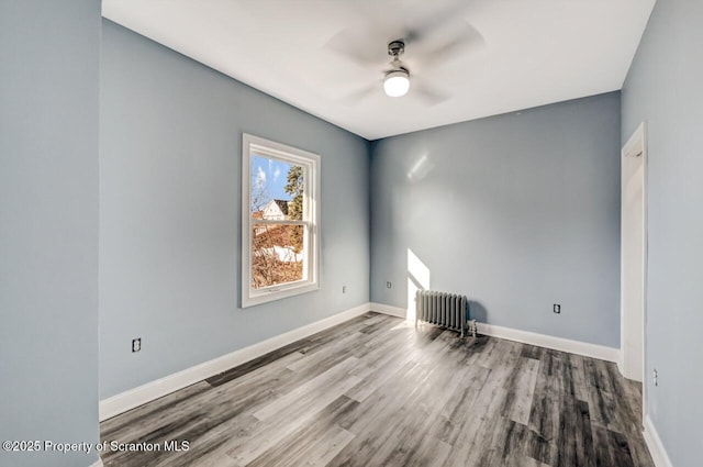 unfurnished room featuring a ceiling fan, baseboards, radiator heating unit, and wood finished floors