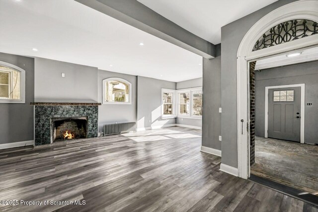 foyer featuring recessed lighting, radiator heating unit, a high end fireplace, wood finished floors, and baseboards