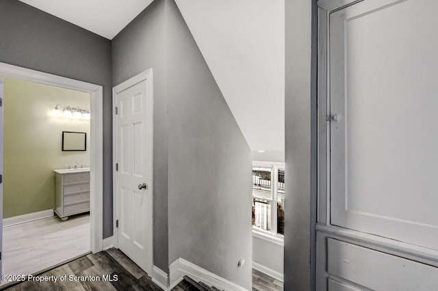 hallway with a sink, baseboards, and wood finished floors