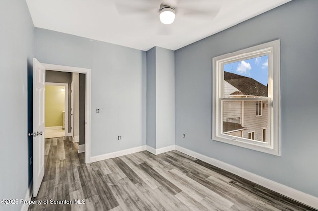 unfurnished room featuring wood finished floors, a ceiling fan, and baseboards