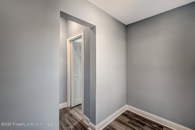 hallway featuring dark wood-style flooring and baseboards