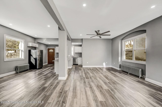 unfurnished living room featuring light wood-type flooring, baseboards, and radiator heating unit