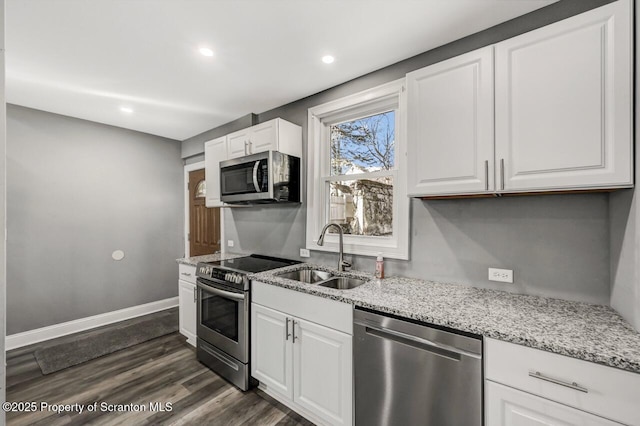 kitchen featuring light stone countertops, white cabinetry, stainless steel appliances, and a sink