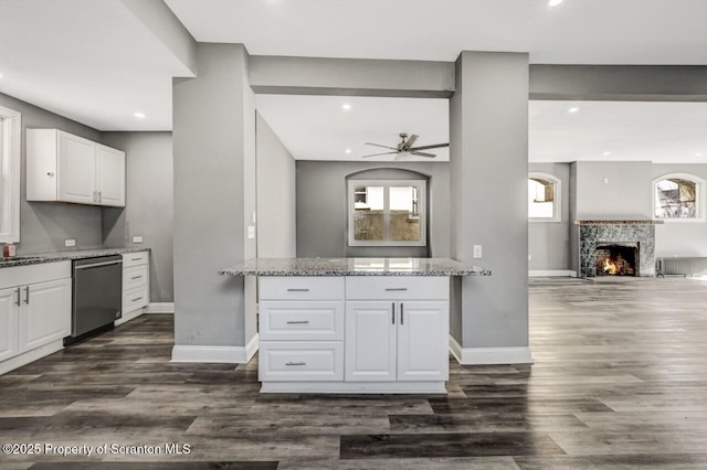 kitchen featuring a tile fireplace, white cabinetry, open floor plan, light stone countertops, and dishwasher