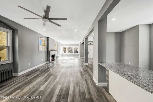 living area featuring baseboards, a fireplace, dark wood finished floors, and radiator