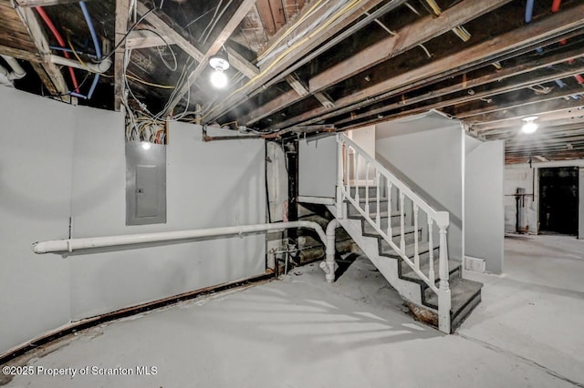 unfinished basement featuring electric panel and stairway