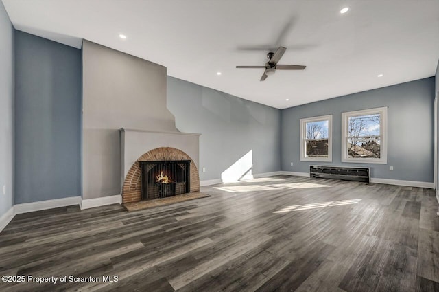 unfurnished living room featuring wood finished floors, recessed lighting, a fireplace with flush hearth, and baseboards