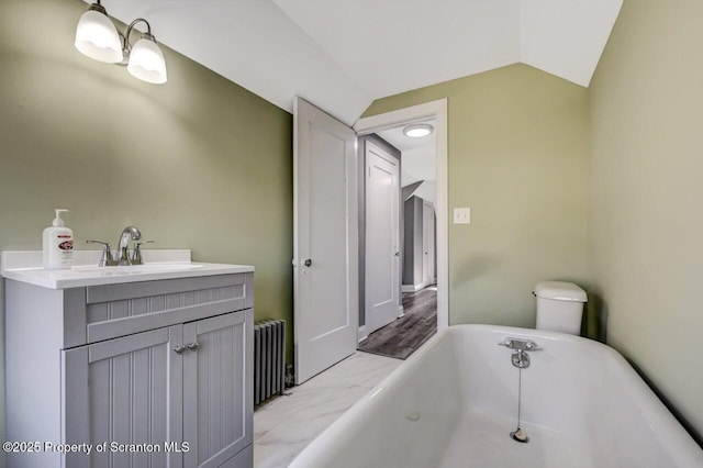 full bathroom featuring vaulted ceiling, a freestanding tub, vanity, and radiator