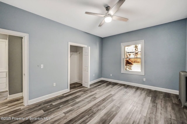 unfurnished bedroom featuring a closet, radiator heating unit, wood finished floors, and baseboards