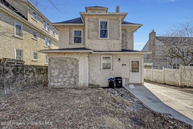 rear view of house featuring fence and stucco siding