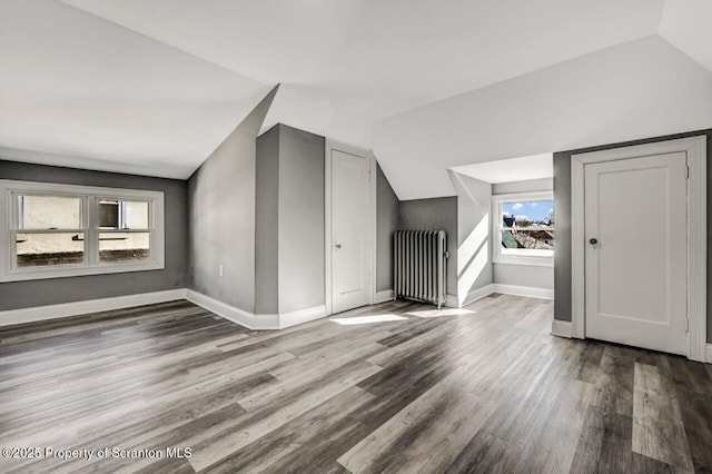 bonus room with radiator, baseboards, vaulted ceiling, and wood finished floors